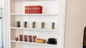 Une étagère blanche, ornée de divers objets décoratifs, et une chaise rose placée devant.