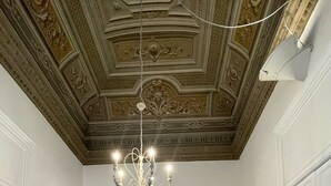 A room with a patterned floor, a sofa, a chandelier, and a lamp. - Donna Franca Florio (Palermo)