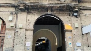 An arched entrance to a building with stone walls and a metal gate. - Donna Franca Florio (Palermo)
