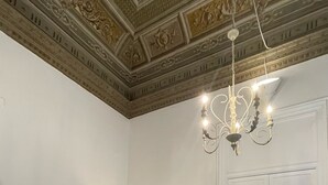 A room with a patterned floor, a beige sofa, a lamp, and a chandelier. - Donna Franca Florio (Palermo)
