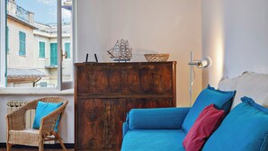 Una habitación acogedora con un armario de madera, un sillón de mimbre y un sofá azul con cojines.