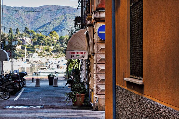 A narrow street with a sign for 'BOUTIQUE' and a view of a marina with boats in the background.