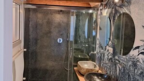 Ein modernes Badezimmer mit Duschkabine aus Glas, Holzboden und einer Wand mit Palmenmuster.