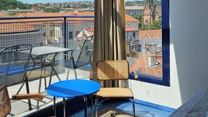 A room with a large skylight, a view of a cityscape, a bed, and a table with chairs. - Hotel Avion - National Cultural Monument - ICONIC HOUSES (Brno)