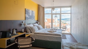 A hotel room with a bed, desk, chair, and large window offering a city view. - Hotel Avion - National Cultural Monument - ICONIC HOUSES (Brno)