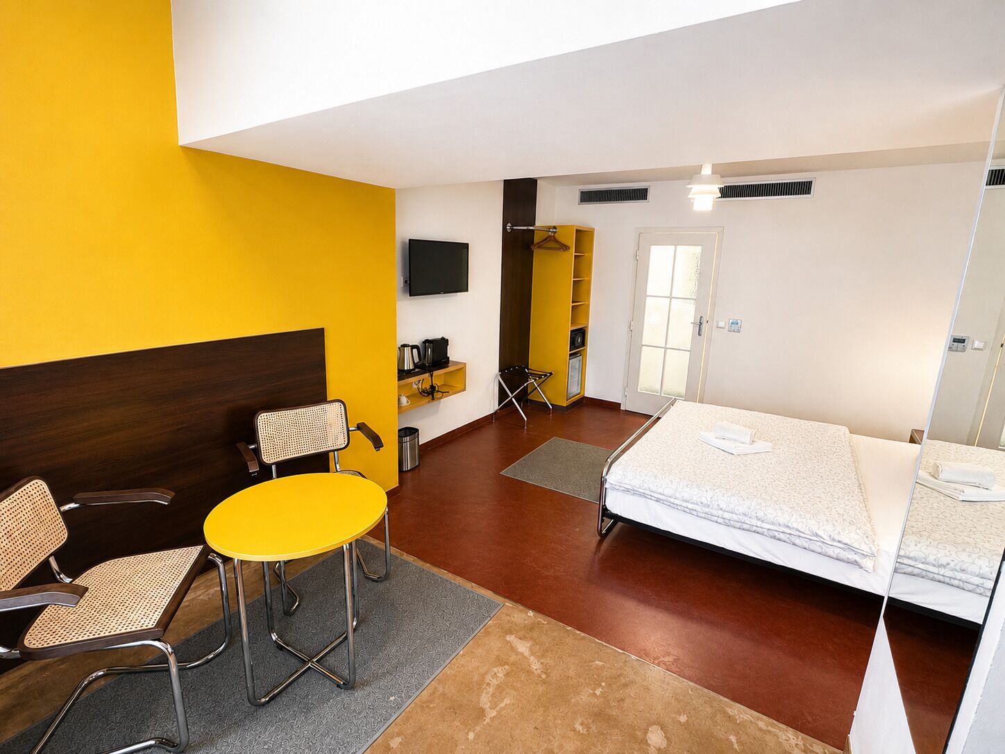 Une chambre d’hôtel comprenant un lit, une chaise, une table, un téléviseur et une armoire.