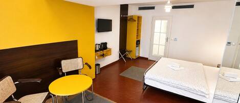 Une chambre d’hôtel comprenant un lit, une chaise, une table, un téléviseur et une armoire.