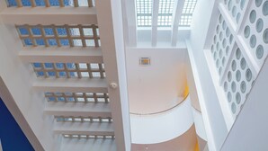 A multi-level interior with a central atrium, glass railings, and a patterned wall. - Hotel Avion - National Cultural Monument - ICONIC HOUSES (Brno)