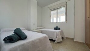 Een hotelkamer met twee bedden, een raam en een nachtkastje.