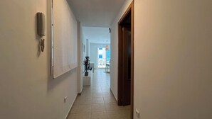 Un passadís estret amb una porta a la dreta i una finestra a l'esquerra.