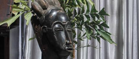 A potted plant with a sculpted head in the foreground, set against a metallic curtain backdrop.