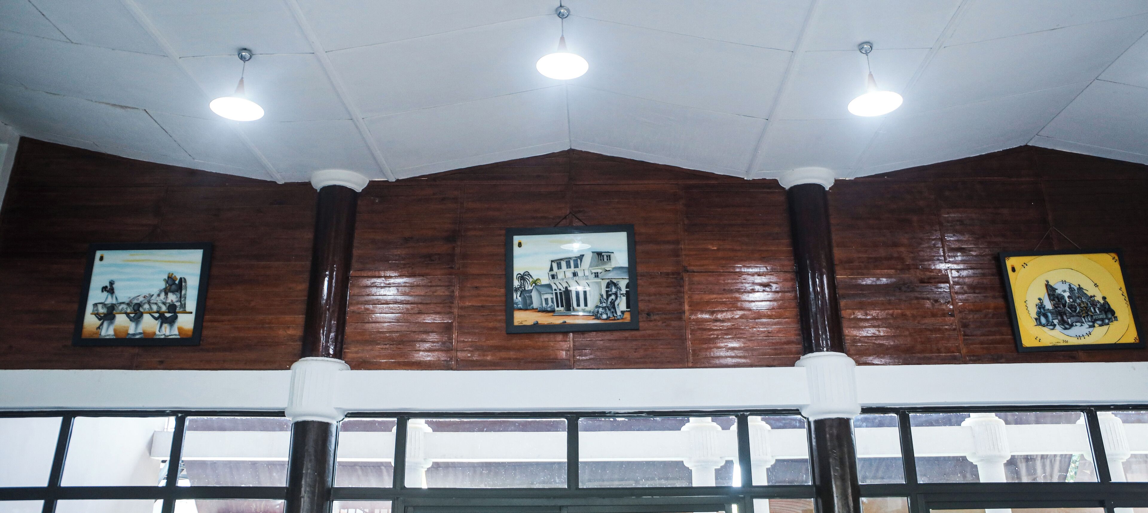 A room with wooden panel walls, ceiling lights, and framed pictures on the wall.