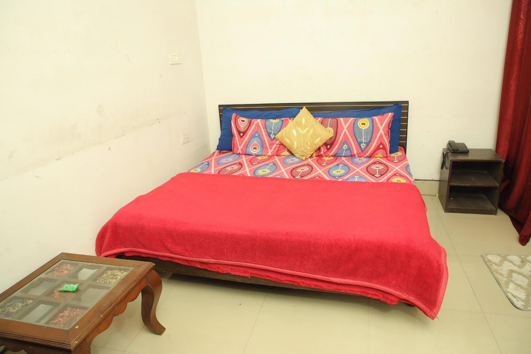 Une petite chambre à coucher, bien rangée, avec un lit simple, une table de chevet et une petite table.