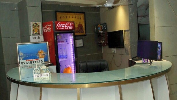 Una reception con un piano in vetro, un frigorifero Coca-Cola, una sveglia e un quadro appeso al muro.