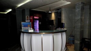 Una reception con un piano in vetro e pannelli bianchi, una macchina distributrice di Coca-Cola e un erogatore d'acqua sullo sfondo.