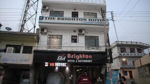 L'Hotel & Ristorante Brighton con una targa, un'auto coperta e un'auto rossa parcheggiata davanti.