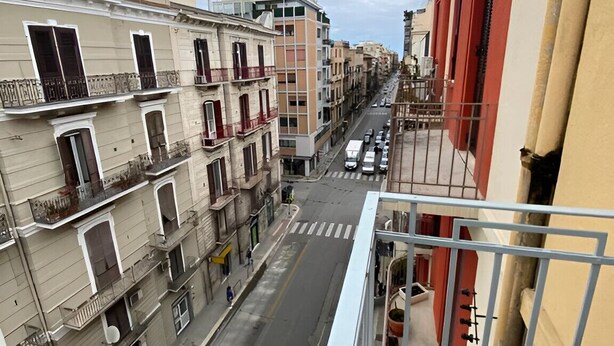 A narrow street between buildings with balconies, a pedestrian crossing, and parked cars. - Bari LandLord 242 (Bari)