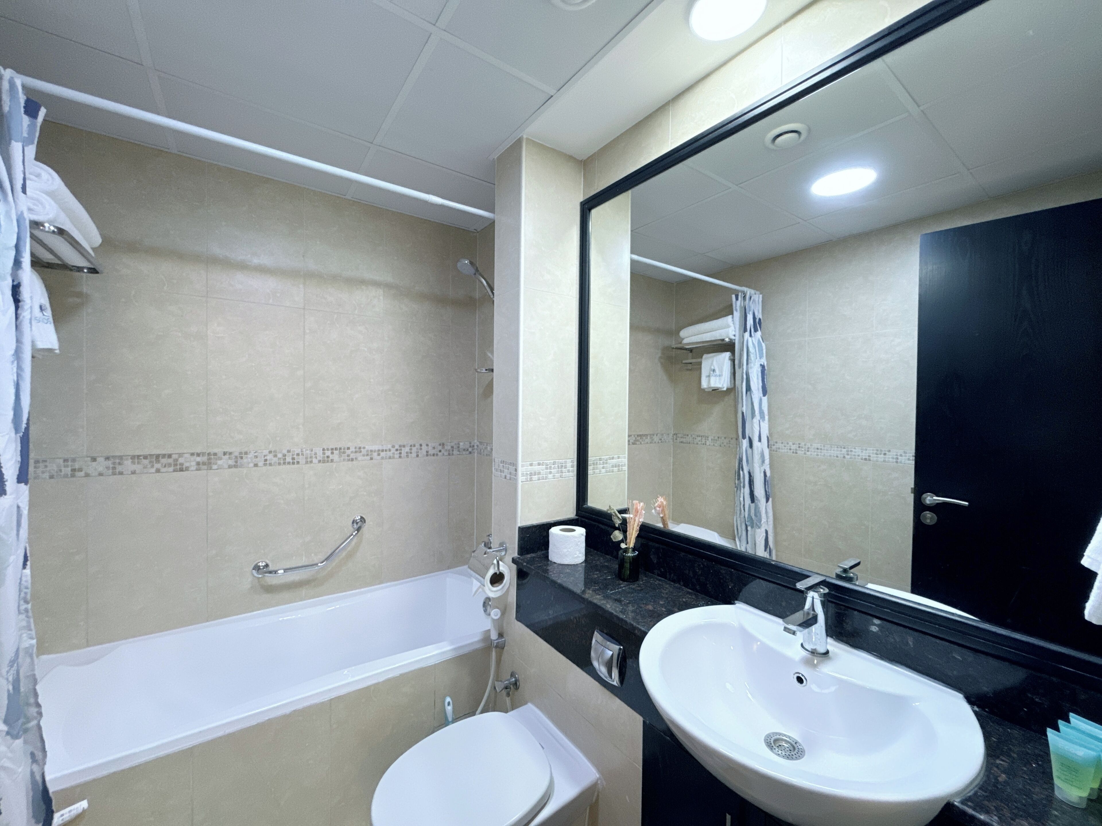 Une salle de bain avec une baignoire, des toilettes, un lavabo et un grand miroir.