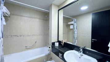 Une salle de bain avec une baignoire, des toilettes, un lavabo et un grand miroir.