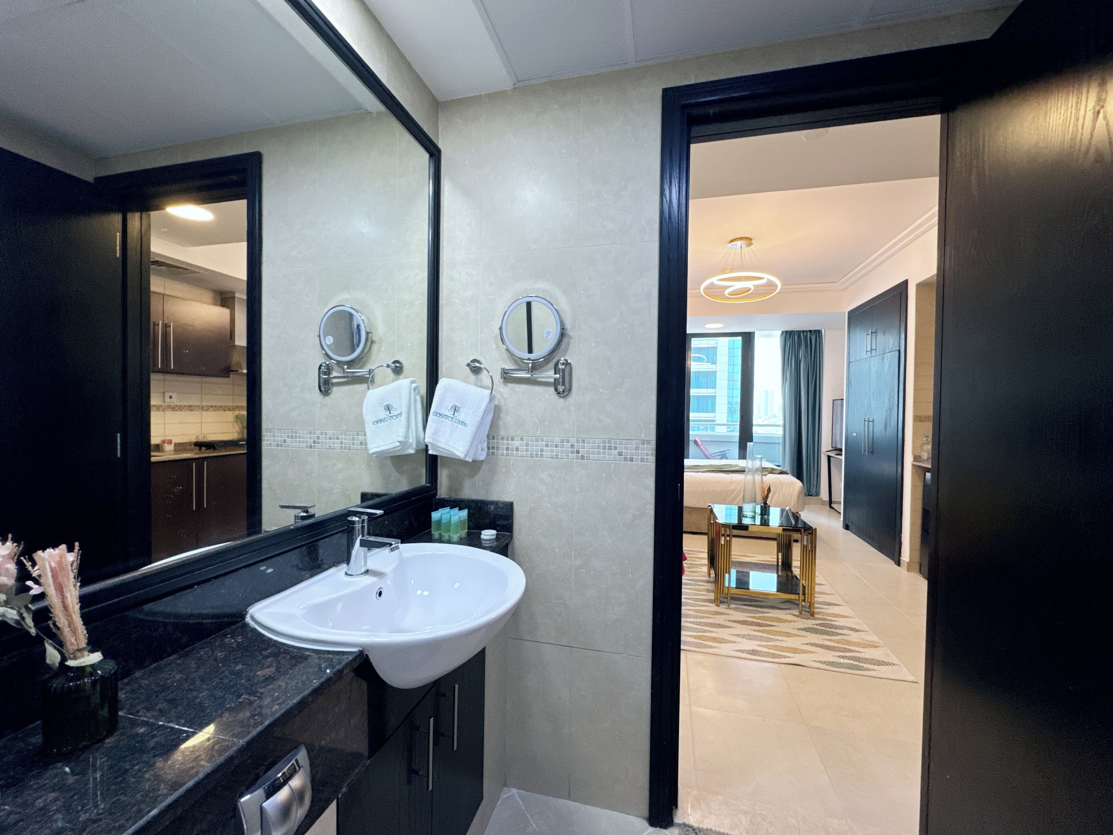 Ein modernes Badezimmer mit Waschbecken, Spiegeln und Blick ins Schlafzimmer.