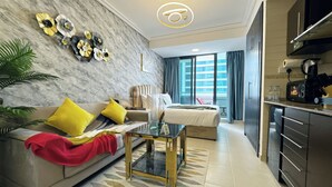 A modern living room with a sofa, coffee table, and decorative wall art. - Cosmos Living Charming Studio With Balco (Dubai)