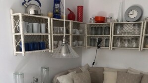 A cozy living room with a white table, a sofa, and shelves with various items. - Apartment Oleander (Novalja)