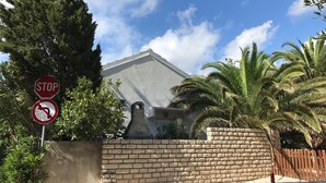 A stop sign and a no U-turn sign in front of a building with a brick wall and palm trees. - Apartment Oleander (Novalja)