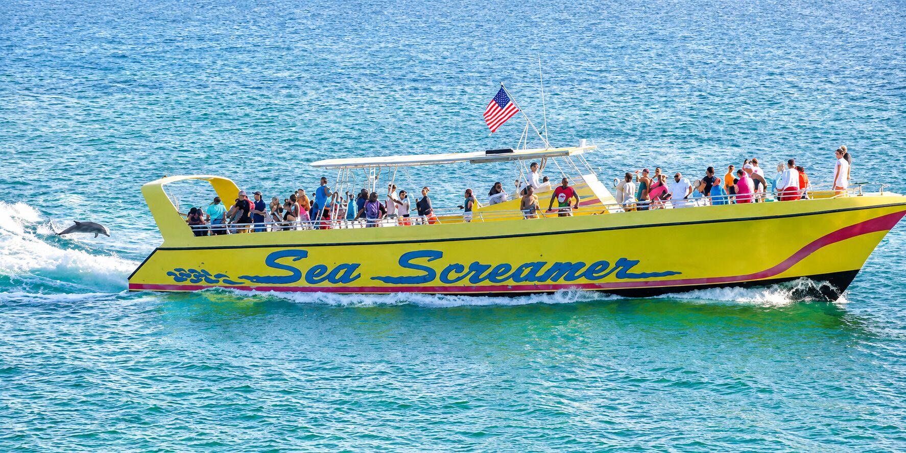 A boat named 'Sea Screamer' with passengers on board, sailing on a body of water.