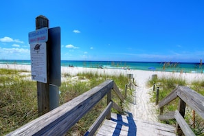 A wooden boardwalk leading to a beach with clear skies.