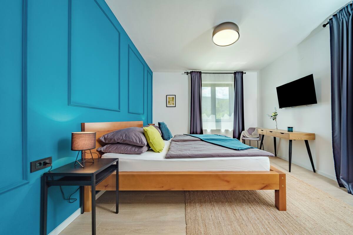 Ein modernes Schlafzimmer mit einem hölzernen Bett, einem Schreibtisch und einem Fernseher.