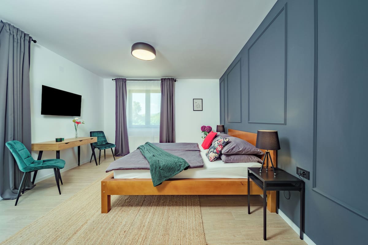 Ein modernes Schlafzimmer mit Bett, Nachttisch, Lampe und Schreibtisch mit Stühlen.