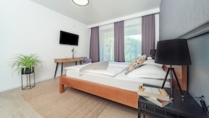 A modern bedroom with a wooden bed, a bedside table, a lamp, a TV, and a potted plant. - PLITVICE LACUS (Rakovica)