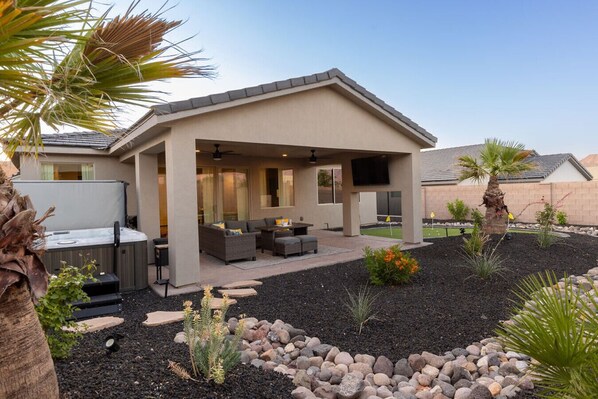A modern house with a covered patio, outdoor seating, and a hot tub.
