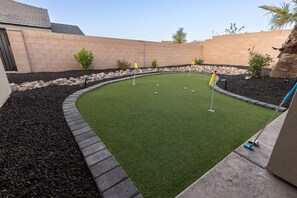 Un campo de mini golf con césped artificial verde, un trazado curvo y algunas banderas que marcan los hoyos.