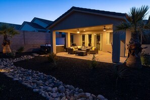 A modern house with a patio area featuring outdoor furniture and a ceiling fan.