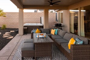 Un área de patio al aire libre con un conjunto de sofás, un jacuzzi y una parrilla.