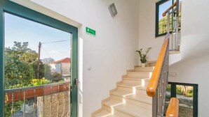 A staircase with wooden handrails, a green door with a sign, and a view of greenery outside. - 4B Apartments (Dubrovnik)