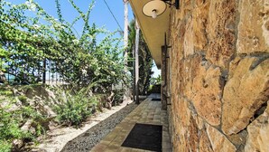 A stone pathway leading to a building with a stone wall and a light fixture. - Zuccheri Canditi by Interhome (Augusta)