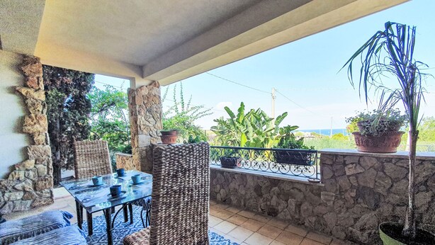An outdoor patio with stone walls, a table with chairs, and potted plants. - Zuccheri Canditi by Interhome (Augusta)