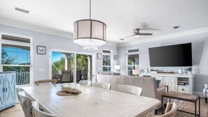 A spacious dining area with a large table and chairs, a chandelier, and a ceiling fan. - Sea Lover - 5 BR Gulf View Getaway with Pool, Pets (Panama City BeachF)