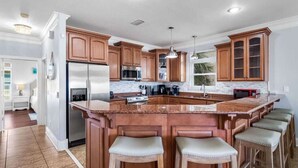 A spacious kitchen with a large island, wooden cabinets, stainless steel appliances, and bar stools. - Sea Lover - 5 BR Gulf View Getaway with Pool, Pets (Panama City BeachF)