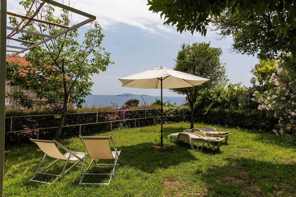Ein Garten mit einer Pergola, Gartenmöbeln und Meerblick.