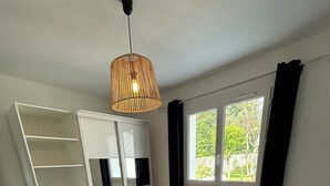 Ein Schlafzimmer mit Bett, Kleiderschrank, Fenster und einer Pendelleuchte.