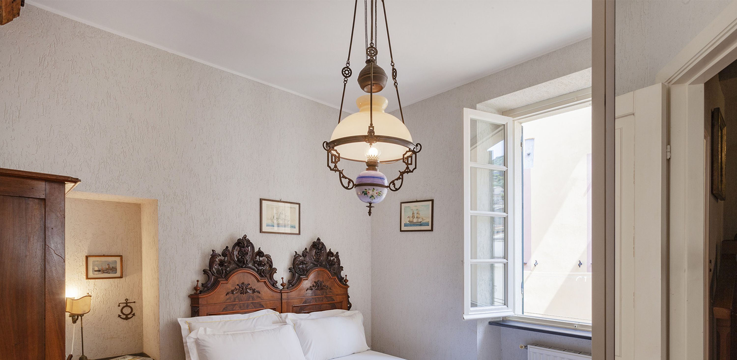 Ein Schlafzimmer mit einem hölzernen Bett, einer Pendelleuchte und zwei gerahmten Bildern an der Wand.