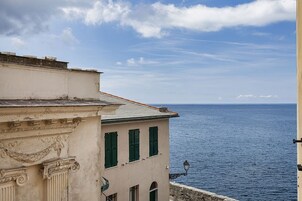 Ein Küstengebäude mit klassischer Architektur, einem Balkon und Blick aufs Meer.