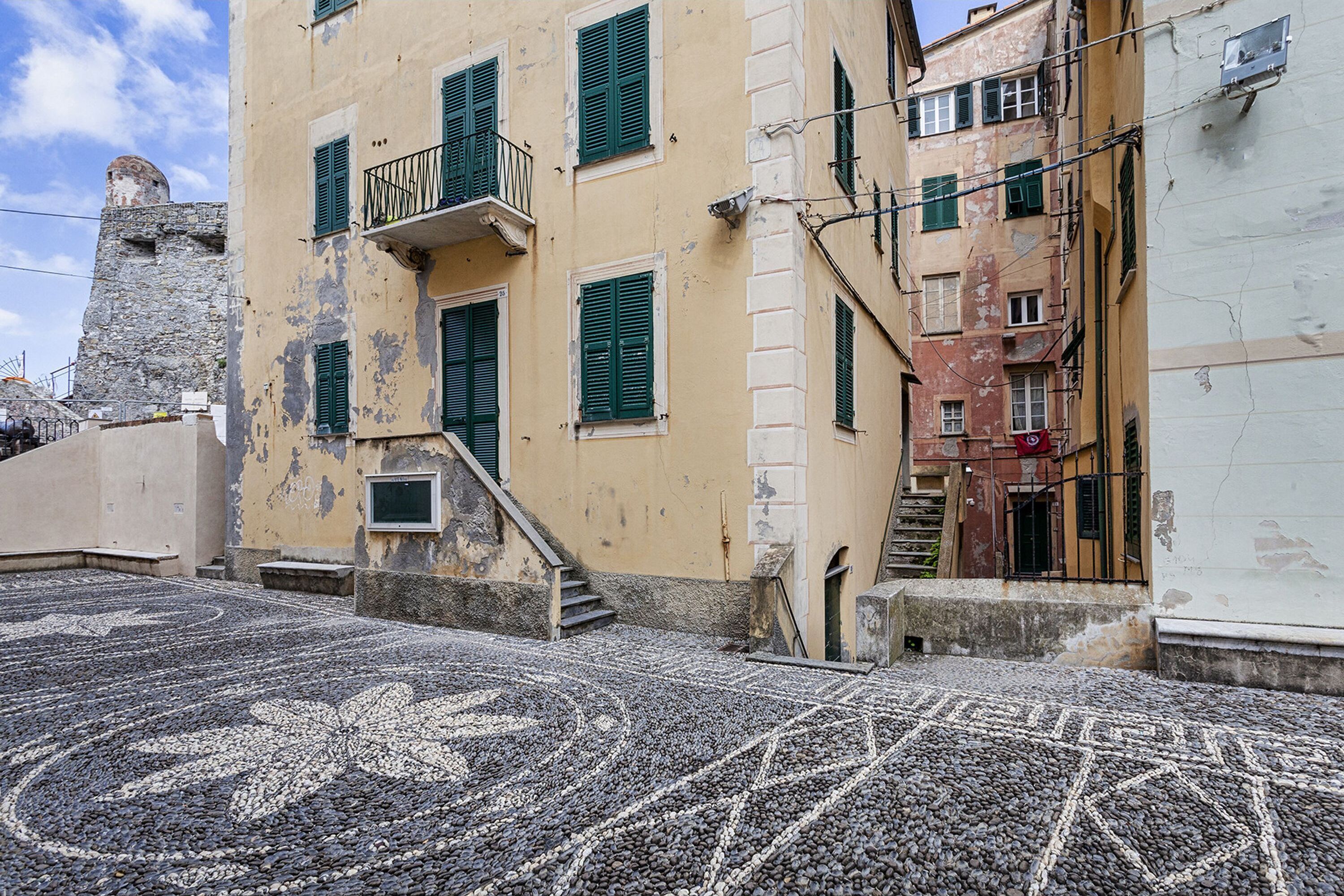 Une rue pavée bordée d’immeubles dotés de balcons et surmontée d’une tour en pierre.