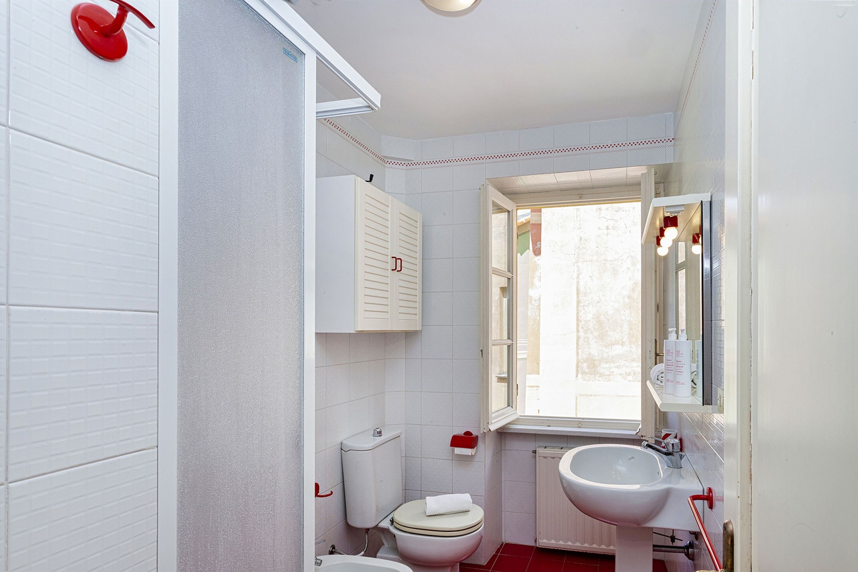 Une salle de bain avec des toilettes, un lavabo et une fenêtre.