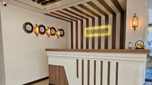 A reception desk with a clock, a BayPark Hotel sign, and a wall-mounted light fixture. - Baypark Hotel & Spa (Midyat)