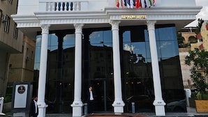 A white hotel with a classical facade, multiple balconies, and flags at the entrance. - Baypark Hotel & Spa (Midyat)