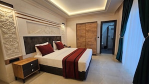 A modern hotel bedroom with a large bed, a nightstand, a wooden wardrobe, and a bathroom visible through an open door. - Baypark Hotel & Spa (Midyat)